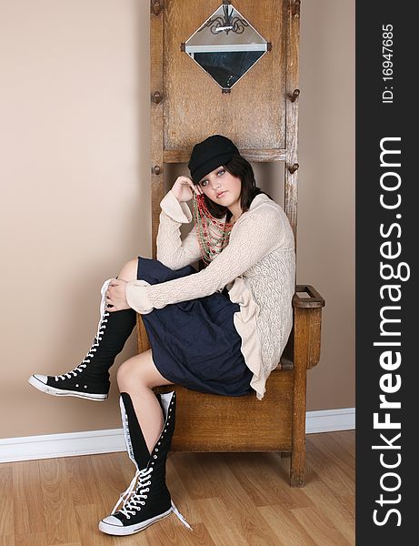 Beautiful brunette teen daydreaming, sitting on an antique coathanger. Beautiful brunette teen daydreaming, sitting on an antique coathanger