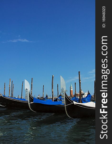 Anchored gondolas in Venetian lagoon with tower in the background. Anchored gondolas in Venetian lagoon with tower in the background