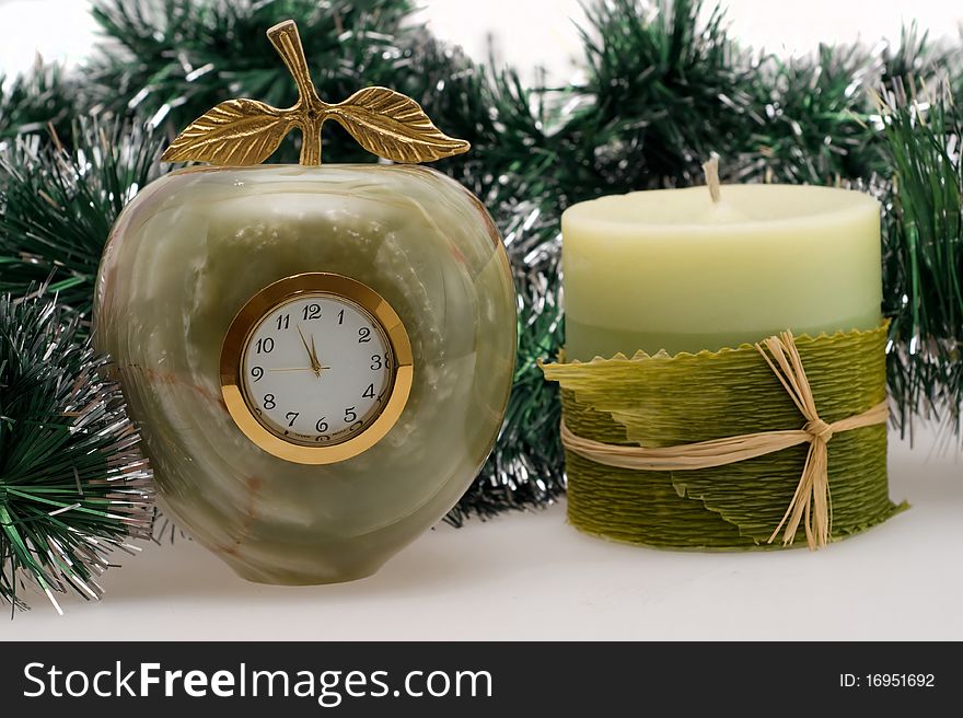 Candle and Desktop clock shows three minutes before the New year with Christmas garlands. Candle and Desktop clock shows three minutes before the New year with Christmas garlands