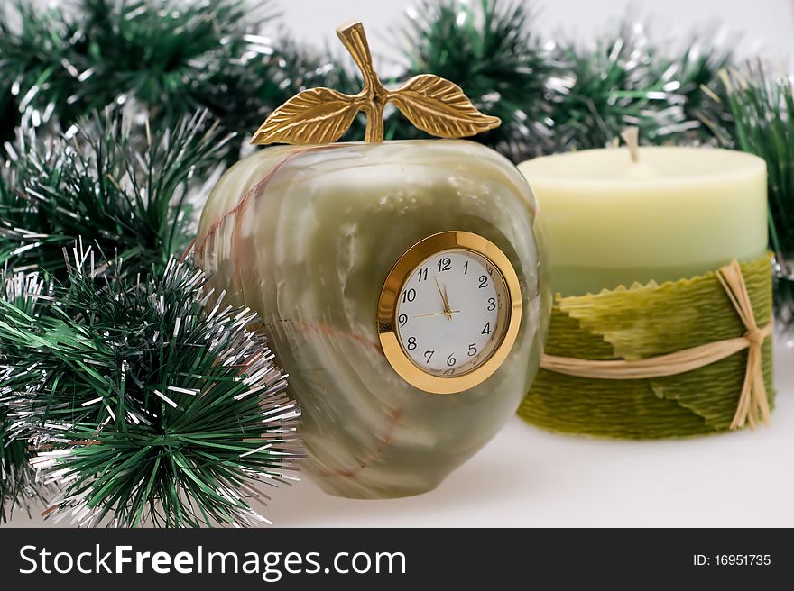 Candle and Desktop clock shows three minutes before the New year with Christmas garlands. Candle and Desktop clock shows three minutes before the New year with Christmas garlands