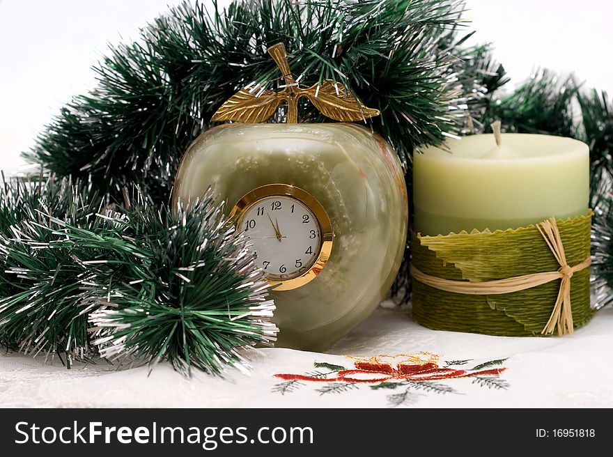 Candle and Desktop clock shows three minutes before the New year with Christmas garlands. Candle and Desktop clock shows three minutes before the New year with Christmas garlands