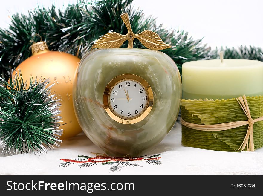 Candle and Desktop clock shows three minutes before the New year with Christmas garlands. Candle and Desktop clock shows three minutes before the New year with Christmas garlands