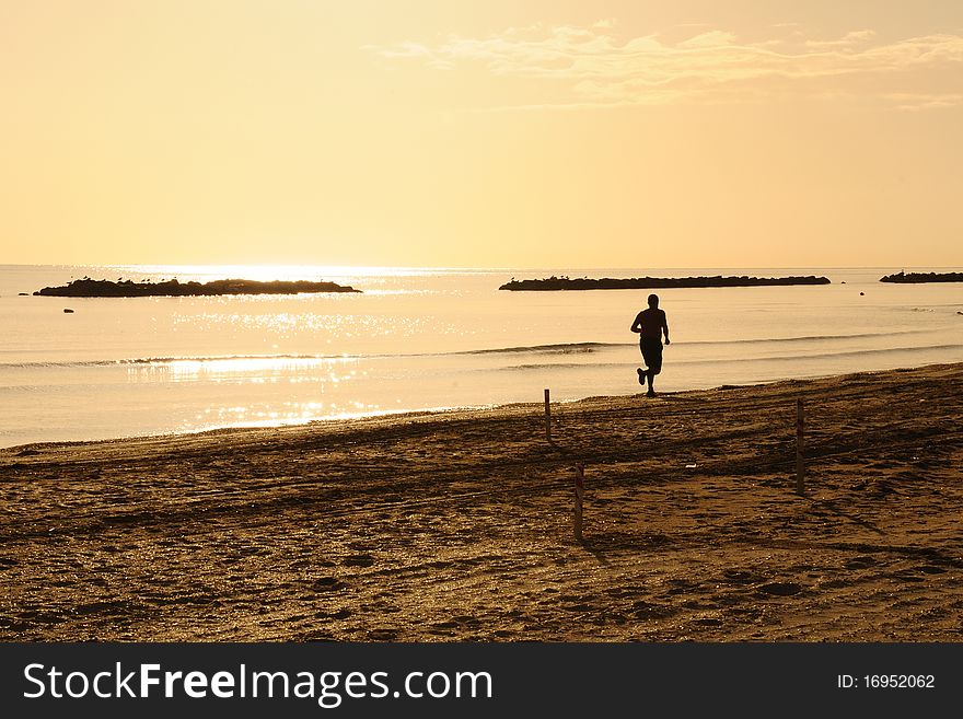 A man making his jogging practice on the seaside at sunset. A man making his jogging practice on the seaside at sunset
