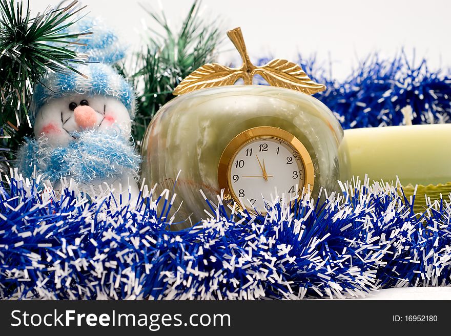 Snowman, candle and Desktop clock shows three minutes before the New year with Christmas garlands. Snowman, candle and Desktop clock shows three minutes before the New year with Christmas garlands