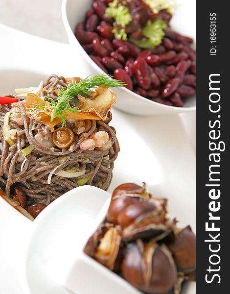 Soba noodles with seafood and mushrooms with roasted chestnuts and beans on a background. Soba noodles with seafood and mushrooms with roasted chestnuts and beans on a background