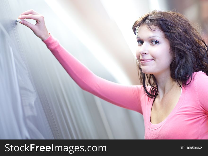 Pretty young college student writing on the chalkboard/blackboard during math class (shallow DOF; color toned image)