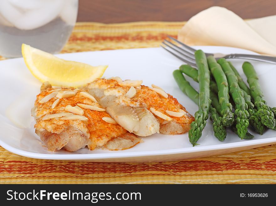 Fish fillets topped with crab meat sauce and almond slivers with asparagus and slice of lemon. Fish fillets topped with crab meat sauce and almond slivers with asparagus and slice of lemon