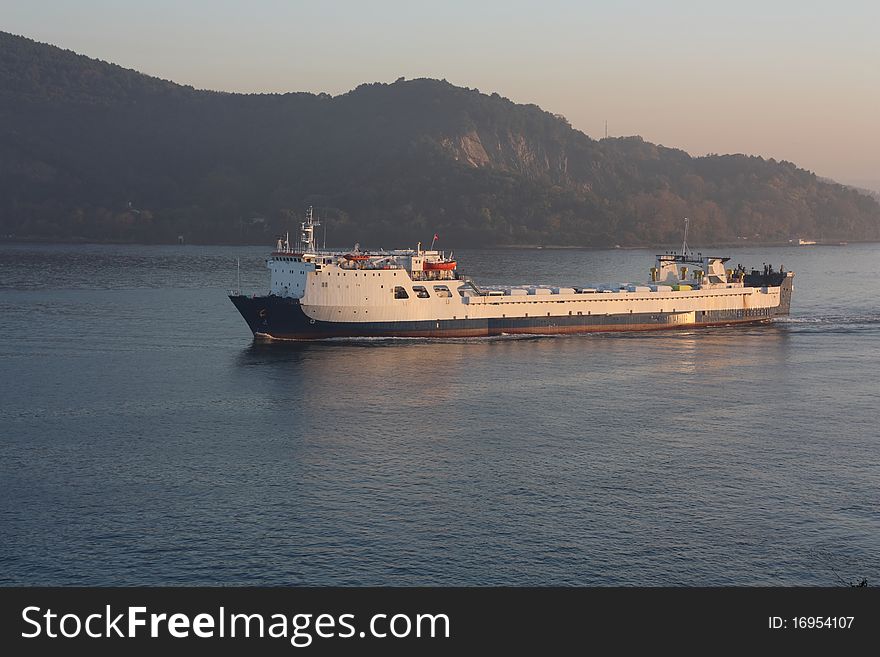 White cargo ship sailing through the Bosphorus in the evening