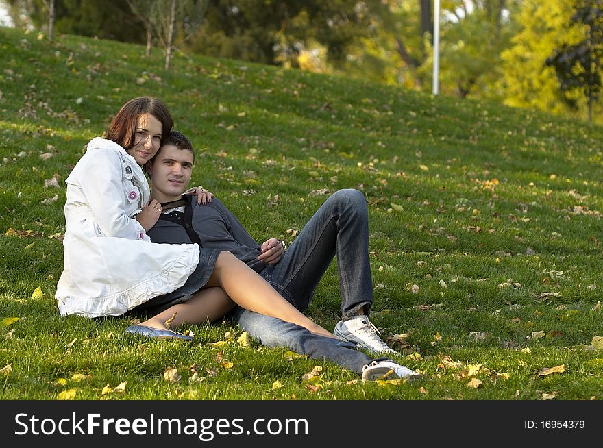 Young couple sitting in the autumn city park (defocused background). Young couple sitting in the autumn city park (defocused background)