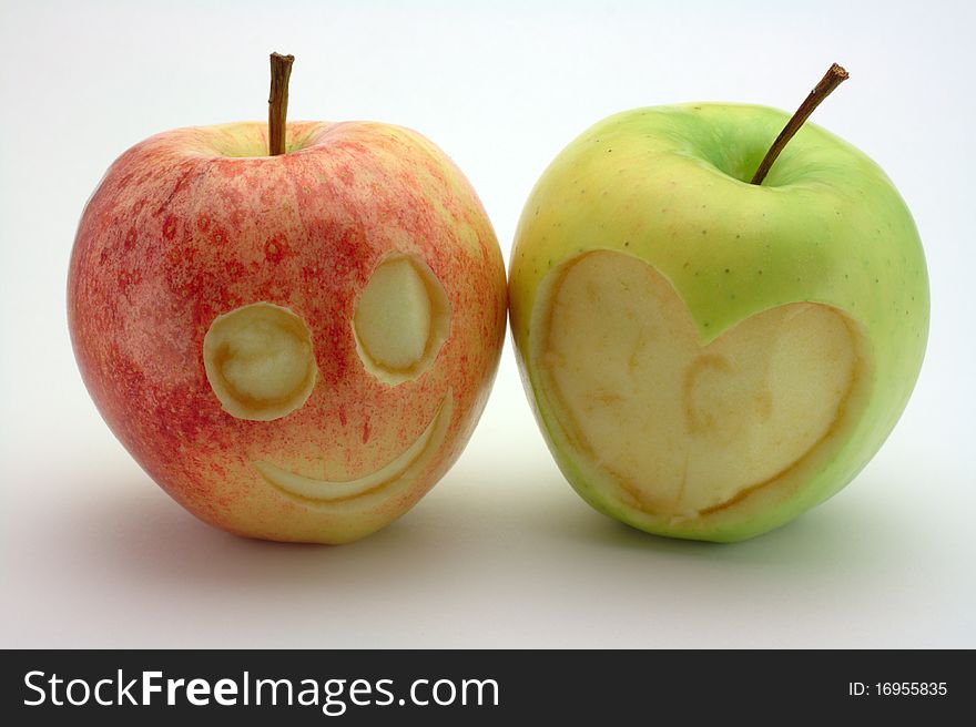 Two carved apples. One is a smiling face the other is a heart. Two carved apples. One is a smiling face the other is a heart