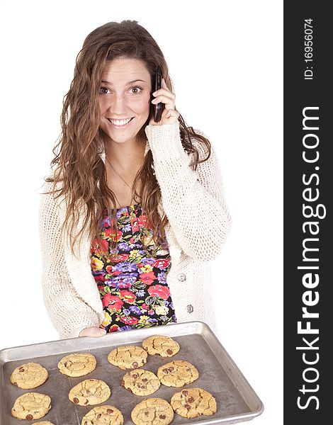 A woman on her phone with a pan of cookies. A woman on her phone with a pan of cookies.