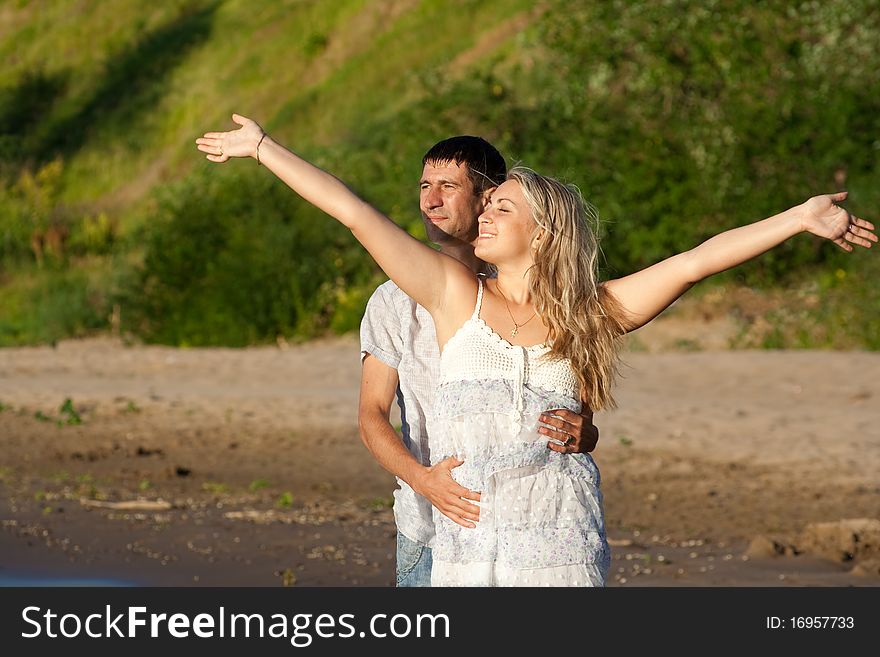 Pair of the enamoured enjoy solar weather on river bank. Pair of the enamoured enjoy solar weather on river bank