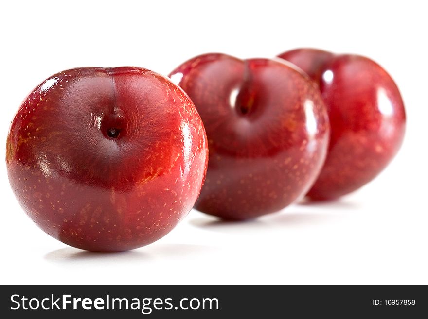 A row of fresh plums on a white background.