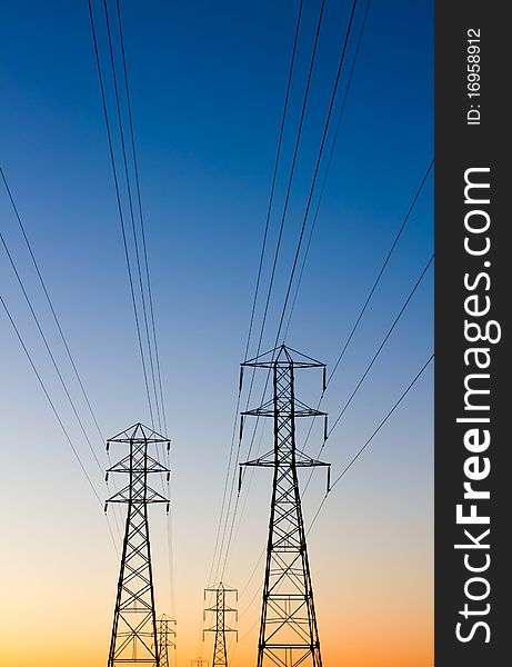 Electrical transmission towers at daybreak with brilliant blue sky and orange sunrise. Electrical transmission towers at daybreak with brilliant blue sky and orange sunrise.