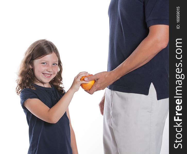 A cute little girl smiles as her dad gives her an apple for a snack. A cute little girl smiles as her dad gives her an apple for a snack