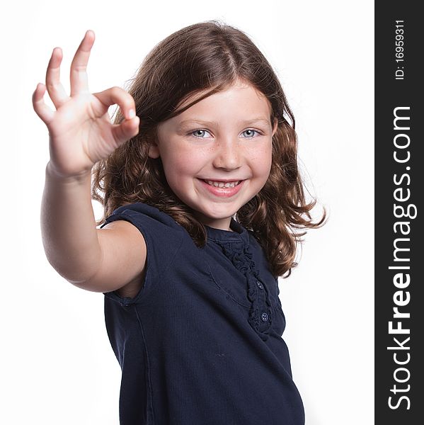 A cute little girl with curly hair and freckles gives an O.K. sign while smiling. A cute little girl with curly hair and freckles gives an O.K. sign while smiling