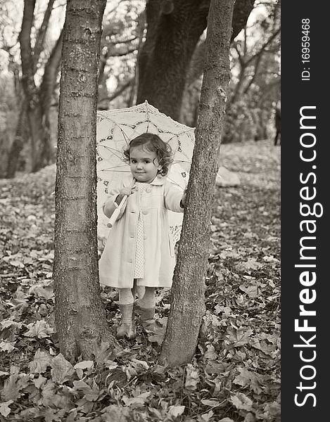 Little girl with umbrella in the park in autumn