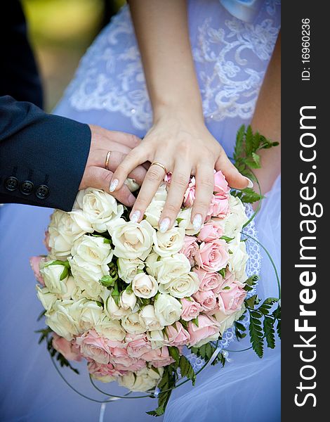 The groom' and the bride's hands on the wedding bouquet