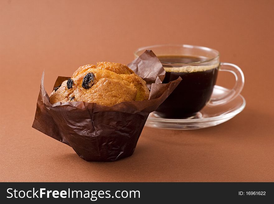 Cup of coffee and cupcake on brown background. Cup of coffee and cupcake on brown background