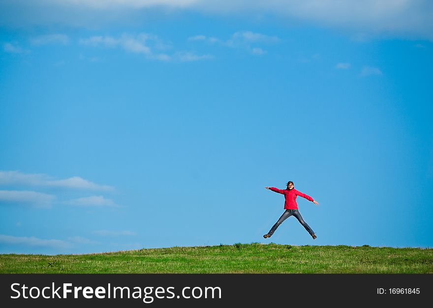 Joyful young woman jumping in the midlle of a green field