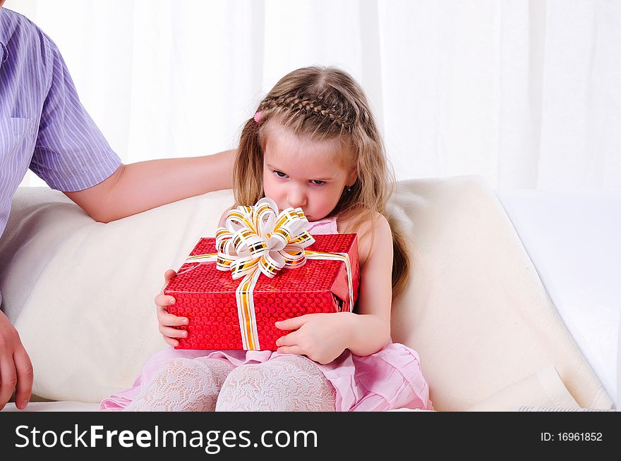 The father gives his young daughter in a red gift box with a white ribbon.