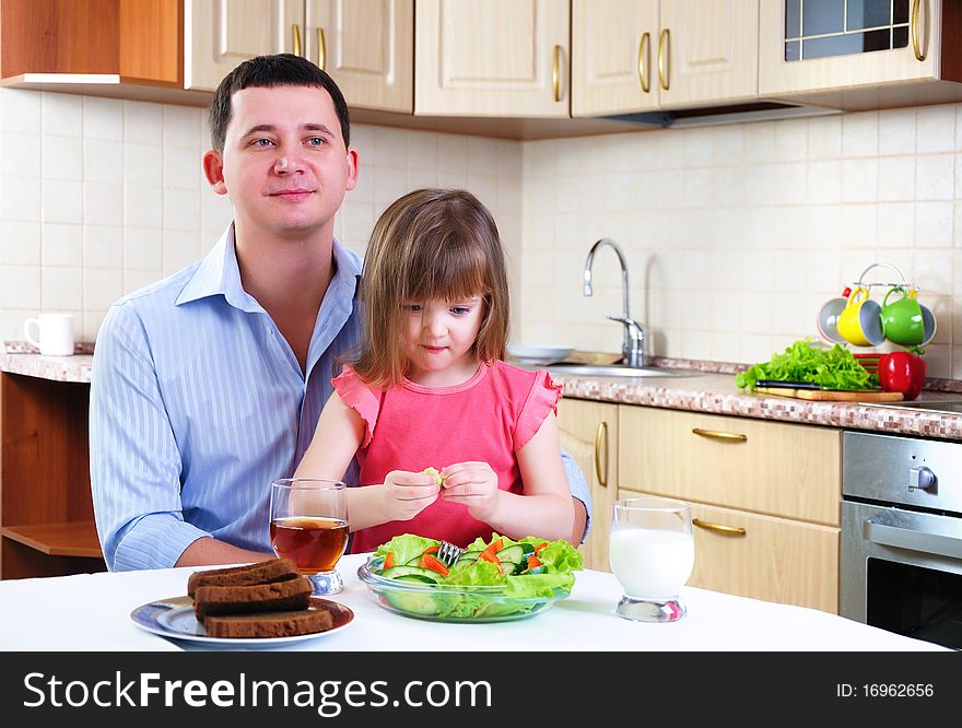 Father and his young daughter eat breakfast together in his kitchen.