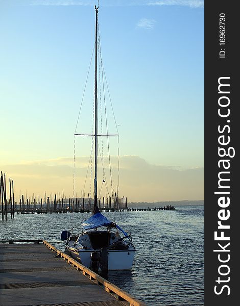 A sailboat in a river at sunset. A sailboat in a river at sunset.