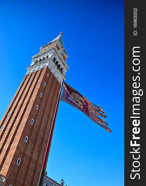 Campanile and Venetian flag against clear, blue sky. Venice, Italy.
