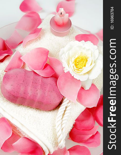 Pink hand made soap and pink rose petals on a white towel. Pink hand made soap and pink rose petals on a white towel