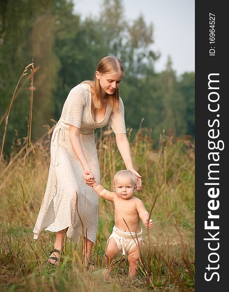 Mother walk with baby in park holding baby by hand