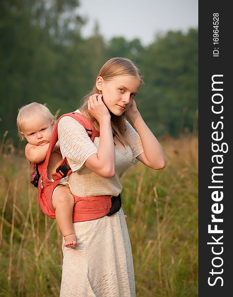 Mother walk with daughter through park at sunset and touching hairs