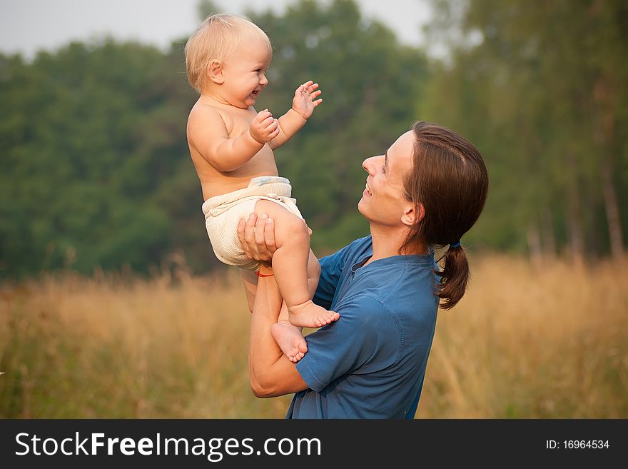 Father holds young baby daughter on hands.