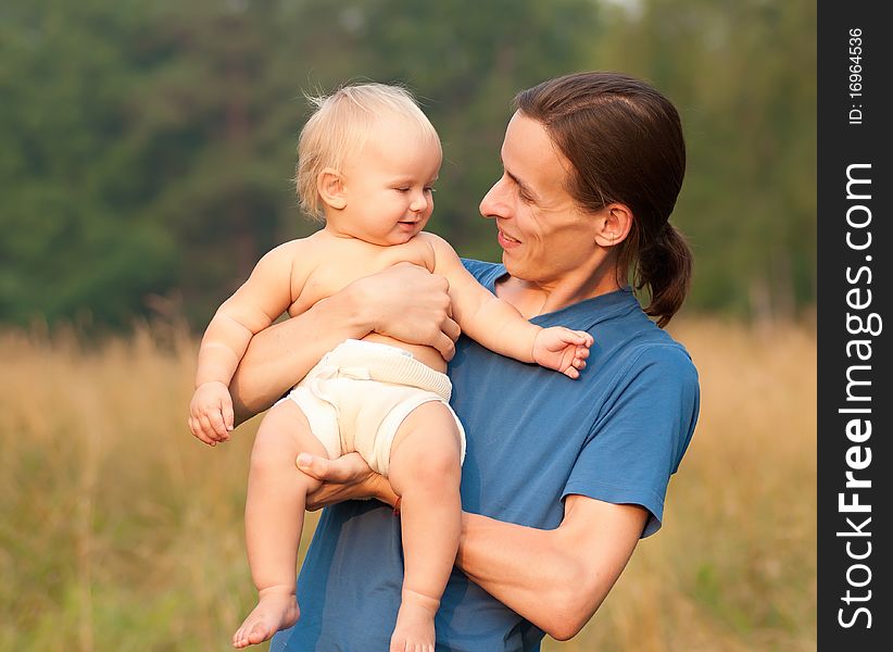 Father holds young baby daughter on hands.