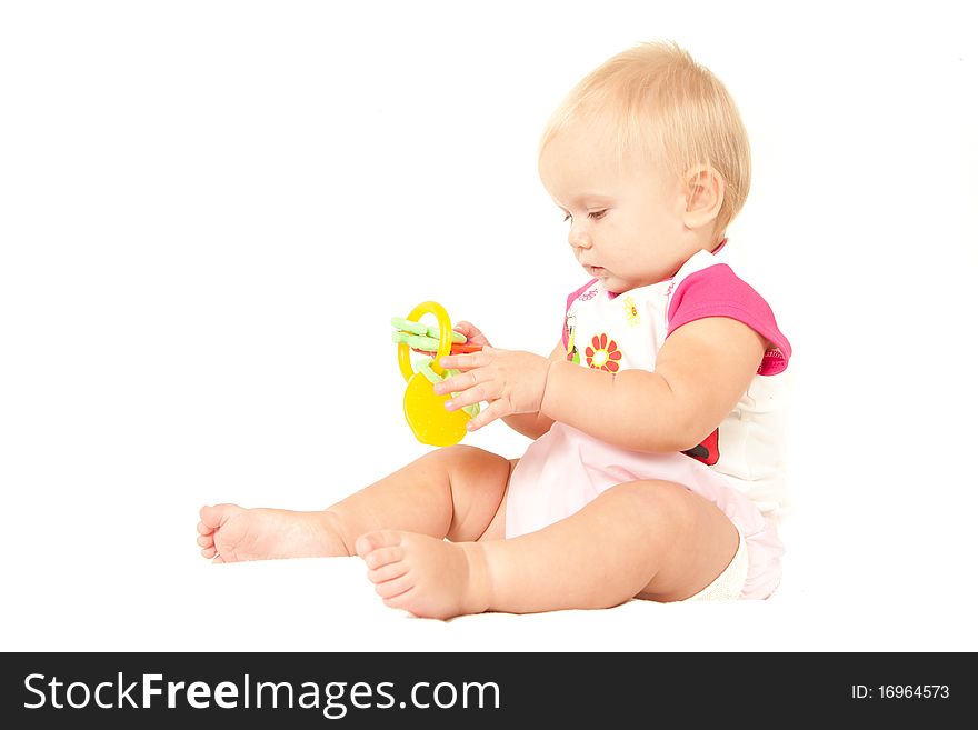 Happy cute baby girl (10 months) sitting on bed and playing with berry toy.