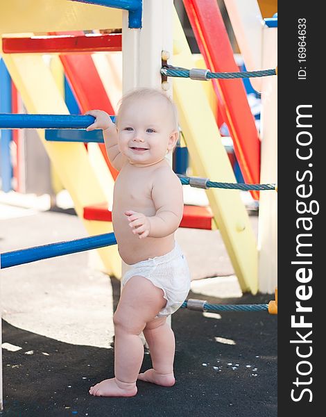 Little baby play on playground holding blue stairs