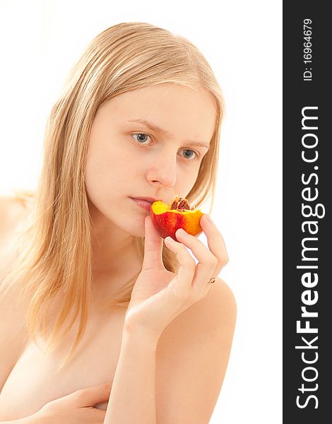 Beautiful young girl eating a peach on white.