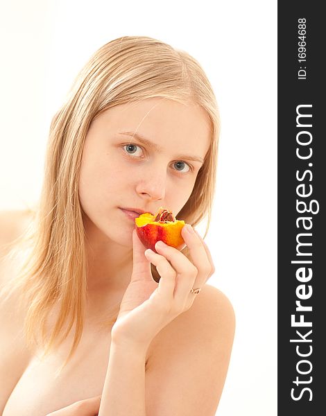 Beautiful young girl eating a peach on white