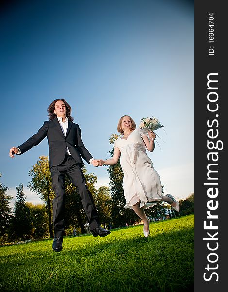 Young wedding lovely couple jump in park with flowers