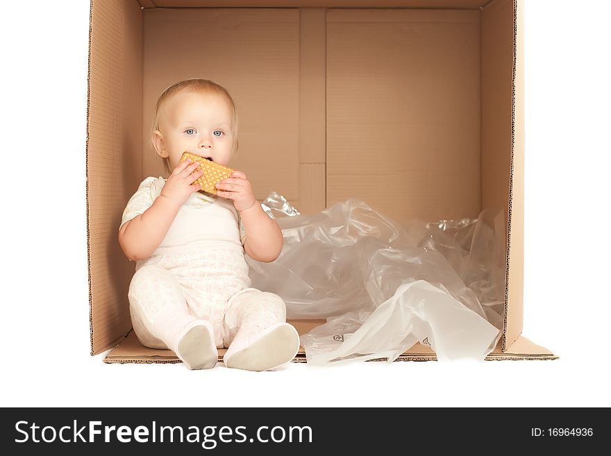 Cheerful young baby sit in paper box and eat cookie. Cheerful young baby sit in paper box and eat cookie