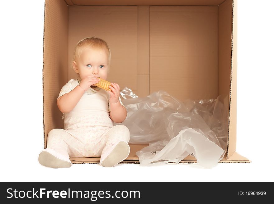 Cheerful young baby sit in paper box and eat cookie on white background