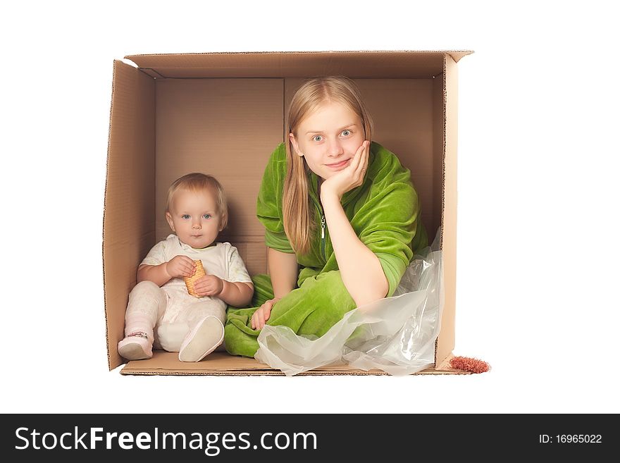 Cheerful mother sit in box with baby eating cookie. Cheerful mother sit in box with baby eating cookie