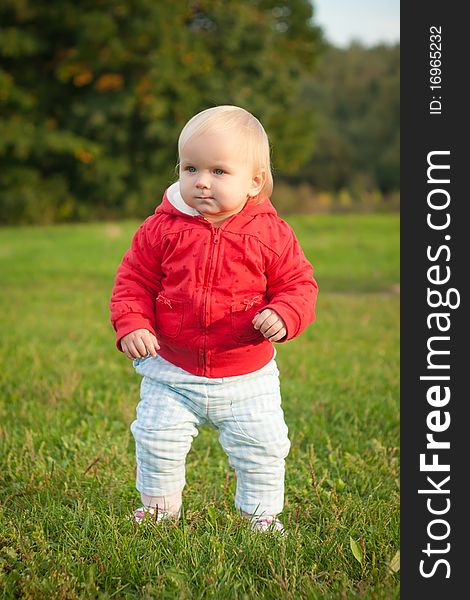 Young cheerful baby walking on the grass in park