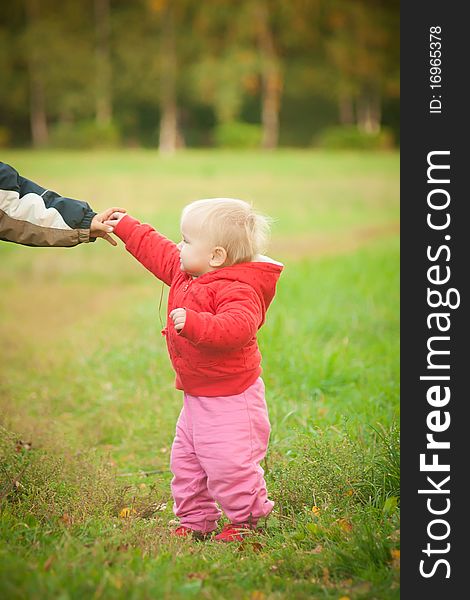 Young adorable baby stay on grass and holding brother hand. Young adorable baby stay on grass and holding brother hand