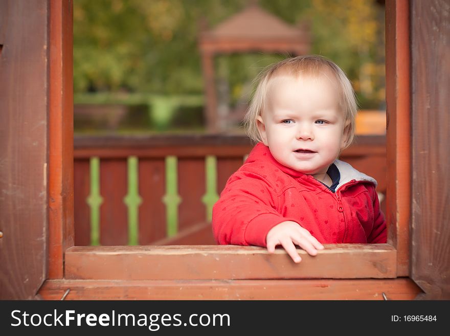 Young cheerful girl look through the window in house on playground