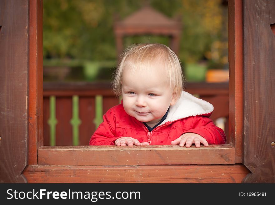 Young cheerful girl look through the window in house on playground