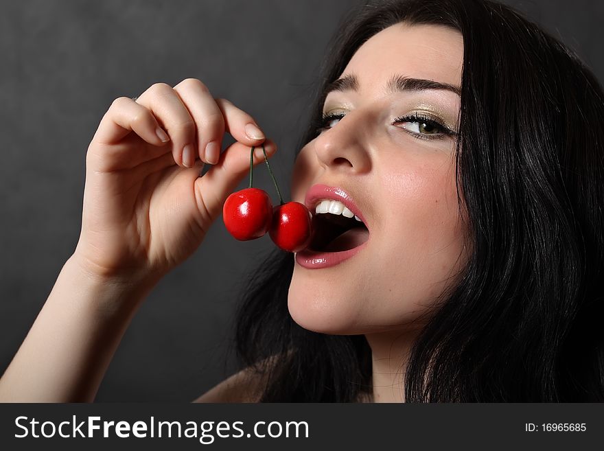 A beautiful girl eats a cherry. A beautiful girl eats a cherry