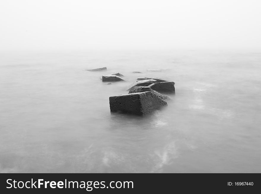 A landscape photo of a sea with white sky and breakwater on the foreground. Shoot in BW. A landscape photo of a sea with white sky and breakwater on the foreground. Shoot in BW.