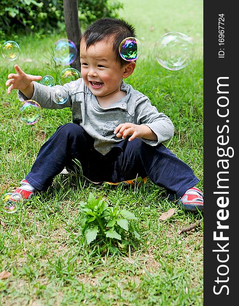 Asian boy playing with soap bubbles.