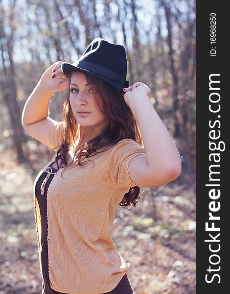 Portrait of a girl in an elegant hat on a background of autumn forest. Portrait of a girl in an elegant hat on a background of autumn forest