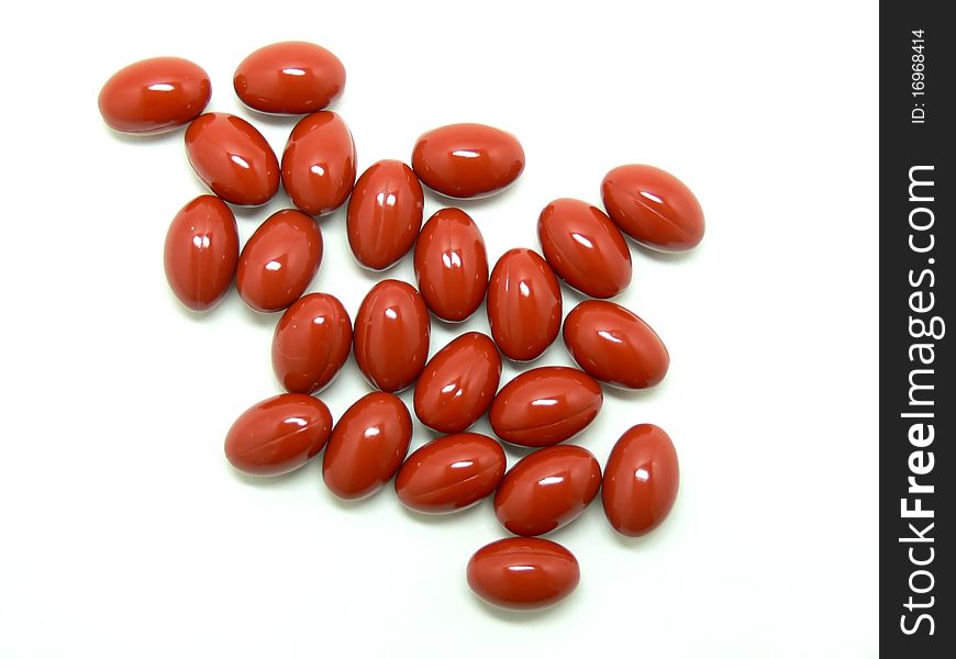 Red vitamin pills on a white background.